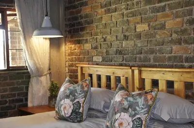 a bedroom with a brick wall and a bed with pillows at Grincourt B&B- with No Load shedding in Polokwane