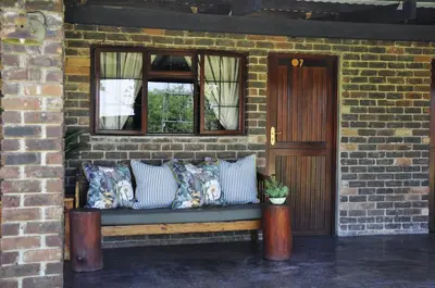 a bench with pillows sitting in front of a brick wall at Grincourt B&B- with No Load shedding in Polokwane
