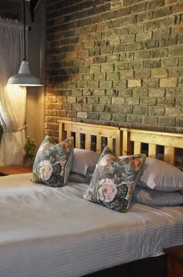 a bed with two pillows and a brick wall at Grincourt B&B- with No Load shedding in Polokwane