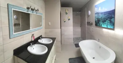 a bathroom with two sinks and a tub and a mirror at Mountain Creek Lodge in Hazyview