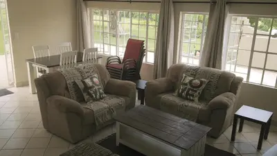 a living room with two chairs and a table at Mountain Creek Lodge in Hazyview