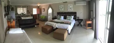 a bedroom with a large bed and a living room at Mountain Creek Lodge in Hazyview