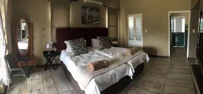 a bedroom with a large bed with white sheets and pillows at Mountain Creek Lodge in Hazyview