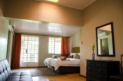 a bedroom with a bed and a mirror and a couch at Mountain Creek Lodge in Hazyview