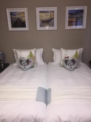 two beds with white sheets and pillows in a bedroom at Mountain Creek Lodge in Hazyview