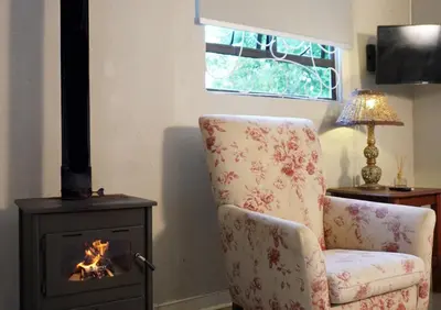 a living room with a chair and a stove at The Browns' Luxury Suites & Cottage in Dullstroom