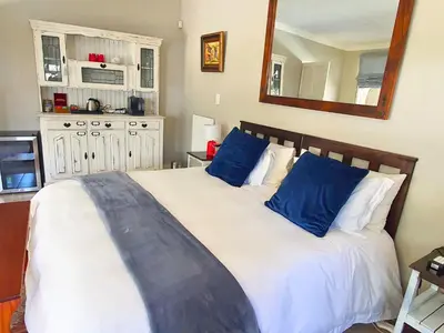 a bedroom with a large bed with blue pillows at The Browns' Luxury Suites & Cottage in Dullstroom