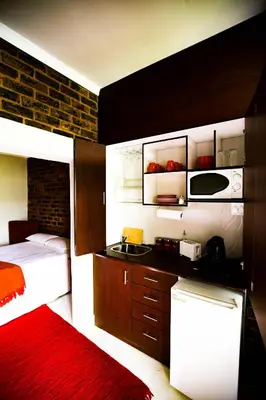 a bedroom with a bed and a kitchen with a sink at Inyameko BnB in Centurion