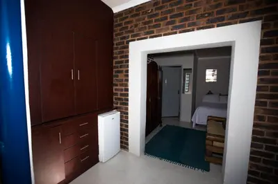 a room with a brick wall and a bedroom at Inyameko BnB in Centurion