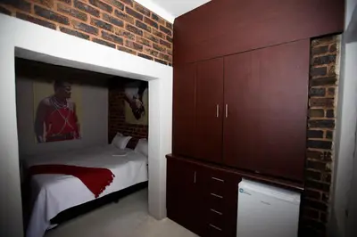 a bedroom with a bed and a brick wall at Inyameko BnB in Centurion