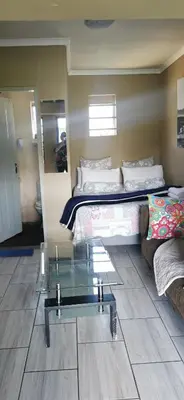 a room with a bed and a couch and a glass table at Inyameko BnB in Centurion