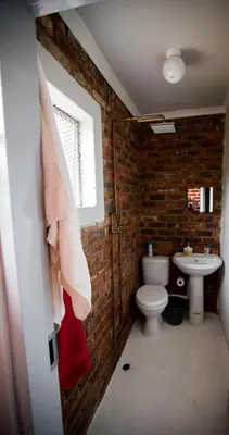 a brick bathroom with a toilet and a sink at Inyameko BnB in Centurion