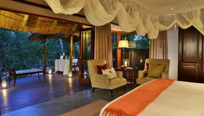 a bedroom with a bed and two chairs and a table at Imbali Safari Lodge in Mluwati Concession