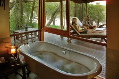 a bath tub in a room with two people sitting at Imbali Safari Lodge in Mluwati Concession