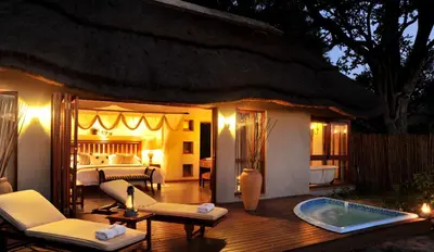 a bedroom with a bed and a jacuzzi tub on a deck at Imbali Safari Lodge in Mluwati Concession