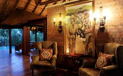 a living room with two chairs and a large painting on the wall at Imbali Safari Lodge in Mluwati Concession