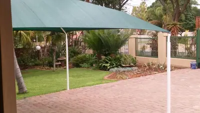 a green umbrella sitting on a brick walk at hanna's place in Polokwane