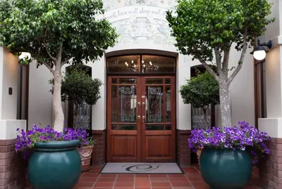 a front door of a building with trees and purple flowers at Oliver`s in White River