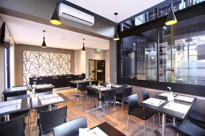 a restaurant with tables and chairs and a large window at Inani Hotel Morning Star in Pretoria