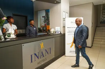 a man in a suit walking past a counter at Inani Hotel Morning Star in Pretoria