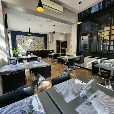 a dining room with tables and chairs in a restaurant at Inani Hotel Morning Star in Pretoria