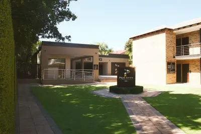 a building with a sign in front of a yard at Palm Swift Luxury Accommodation in Brits