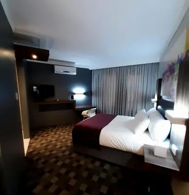 a hotel room with a bed and a television at Palm Swift Luxury Accommodation in Brits