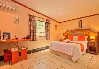 a bedroom with a large bed and a desk at Kruger Adventure Lodge in Hazyview