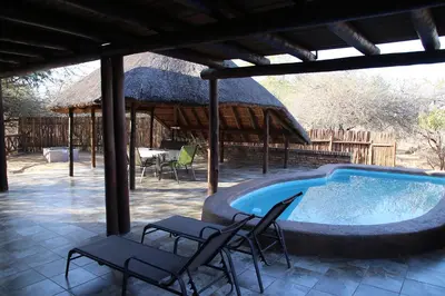 a swimming pool with two chairs and a pavilion at Giraffe plains in Marloth Park