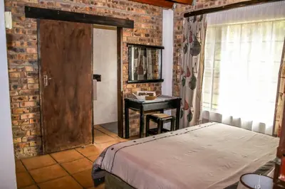 a bedroom with a bed and a table and a mirror at Giraffe plains in Marloth Park