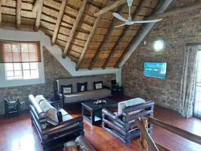 a living room with leather furniture and a brick wall at Giraffe plains in Marloth Park