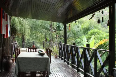 a wooden deck with a table and chairs on it at Old Vic Travellers Inn Nelspruit in Nelspruit