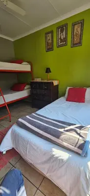 a bedroom with two beds and a green wall at Old Vic Travellers Inn Nelspruit in Nelspruit