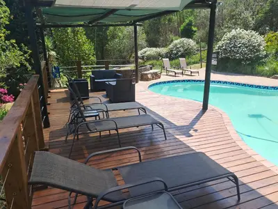 a deck with chairs and an umbrella next to a swimming pool at Sabie Star in Sabie