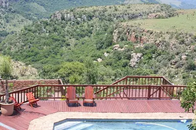 a deck with a swimming pool on top of a mountain at Acra-Retreat Mountain View Lodge in Waterval Boven