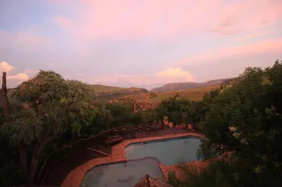 a view of a swimming pool with mountains in the background at Acra-Retreat Mountain View Lodge in Waterval Boven