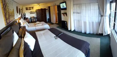 a hotel room with two beds and a couch at Acra-Retreat Mountain View Lodge in Waterval Boven