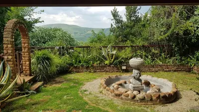 a stone fountain in a yard with some animals in it at Acra-Retreat Mountain View Lodge in Waterval Boven