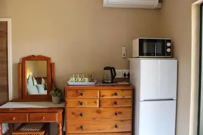 a kitchen with a refrigerator and a dresser with a microwave at Honey Lodge in Klipdrift