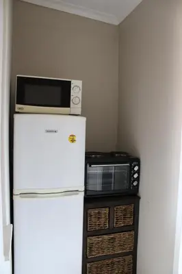 a microwave sitting on top of a refrigerator at Honey Lodge in Klipdrift