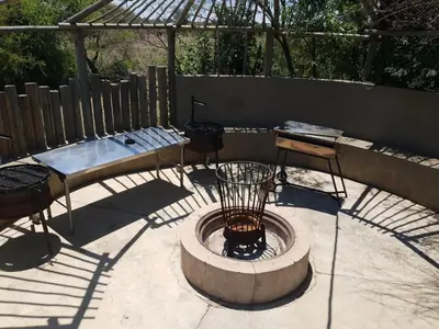 a patio with a bird cage and a table and chairs at Honey Lodge in Klipdrift