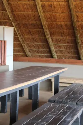 a wooden table in a room with a roof at Honey Lodge in Klipdrift