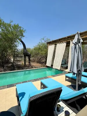 a swimming pool with two chairs and an umbrella at Lindiwe Safari Lodge in Hoedspruit