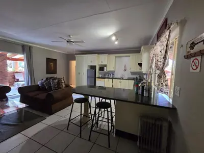 a kitchen and living room with a couch and a table at Lala Bela Guest House in Bela-Bela