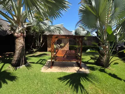 a swing in a yard with palm trees at Lala Bela Guest House in Bela-Bela