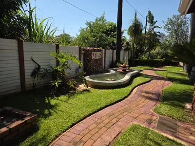 a garden with a brick walkway next to a fence at Lala Bela Guest House in Bela-Bela