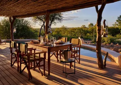 a wooden deck with a table and chairs on it at Geiger's Camp in Timbavati Game Reserve by NEWMARK in Timbavati Game Reserve