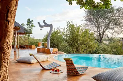a patio with two chairs and a swimming pool at Geiger's Camp in Timbavati Game Reserve by NEWMARK in Timbavati Game Reserve