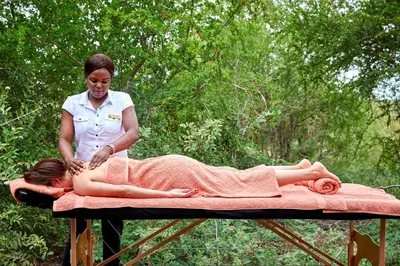 a woman sitting on a bed with a woman laying on at Geiger's Camp in Timbavati Game Reserve by NEWMARK in Timbavati Game Reserve