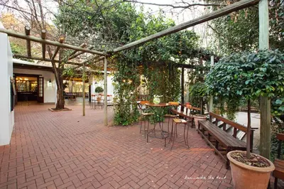 a patio with benches and tables and trees at Kleinkaap Boutique Hotel in Centurion